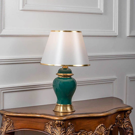 Decorative table lamp with green ceramic base and white fabric shade on wooden table elegant lighting for bedroom decor.