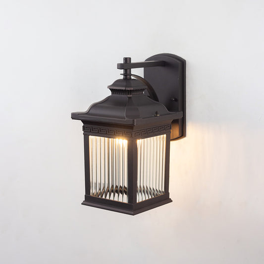 Black metal outdoor wall light on white background with ribbed glass shade casting a warm subtle glow for patio decor.