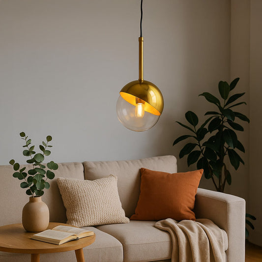 A modern gold and glass pendant light glowing warmly above a beige sofa in a cozy living room with plants and soft cushions creating a calm inviting ambiance.