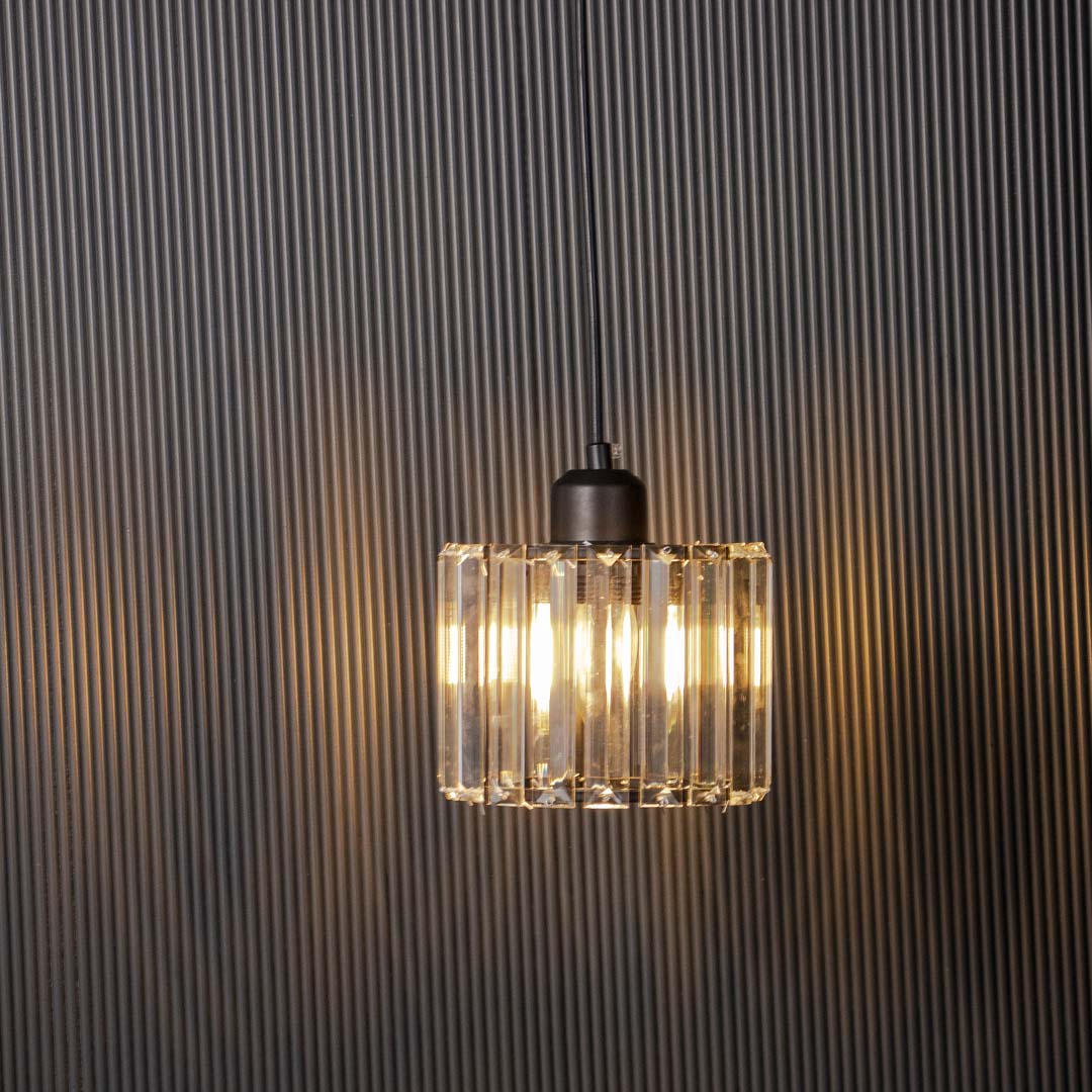 Glass pendant light with ribbed glass shade glowing softly on black background for modern decor.