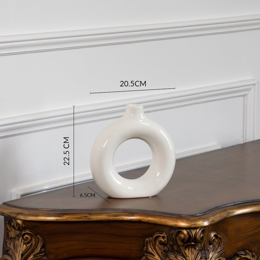White ceramic donut vase measured at 22.5cm height 20.5cm width and 6.5cm depth shown on table with size dimensions.