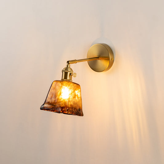 Vintage glass wall light with gold metal arm casting warm glow on neutral wall background perfect for classic interior decor lighting.