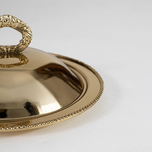 Detailed closeup view of the textured ring handle and beaded rim design on the gold brass serving dish highlighting the craftsmanship.