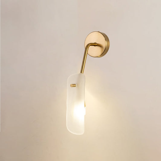 Gold wall light with frosted glass shade glowing softly against a clean white background for modern elegant home lighting decor.