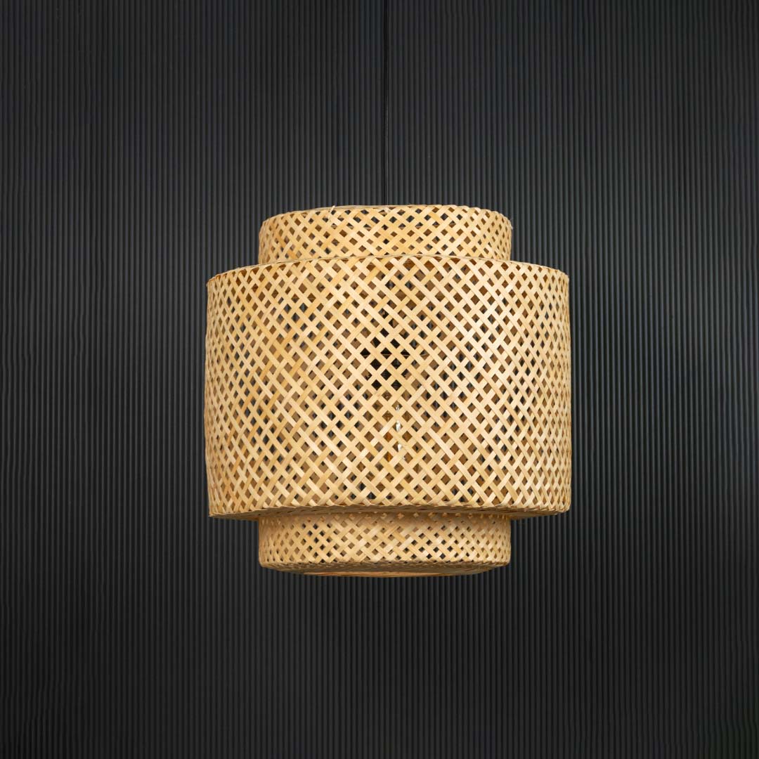 Layered rattan pendant light with handwoven bamboo shade in natural finish turned off against black background.