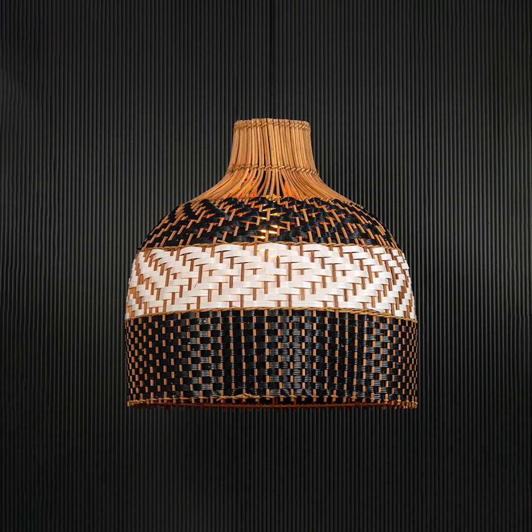 Rattan pendant light illuminated on dark background creating a warm glow through the artistic woven pattern.