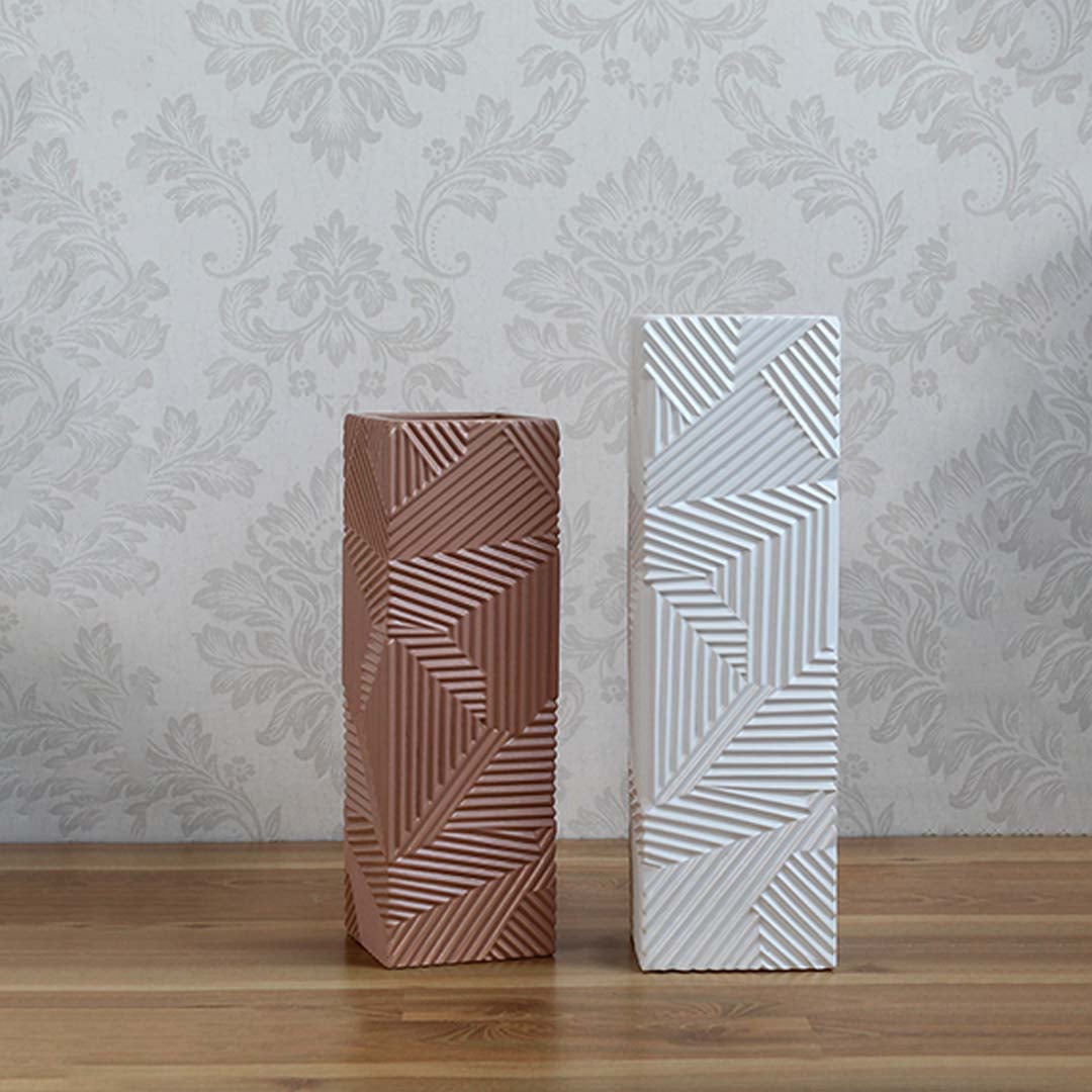 Set of white ceramic vases with geometric embossed patterns arranged together for a coordinated modern home decor display.