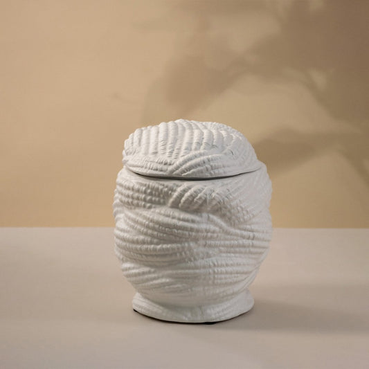 Handcrafted white ceramic vase with a textured pattern glowing gently under light on white background showing artistic craftsmanship.