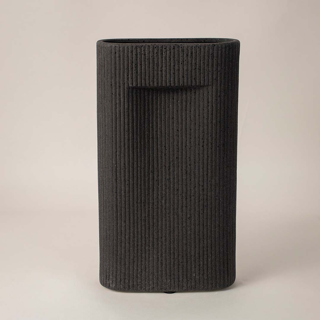 Black ribbed rectangular ceramic vase styled in modern interior setup ideal for elegant living room or office decoration.