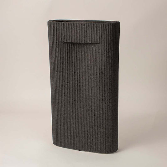 Ribbed black ceramic vase with soft matte finish placed side way showcasing its bold modern silhouette.
