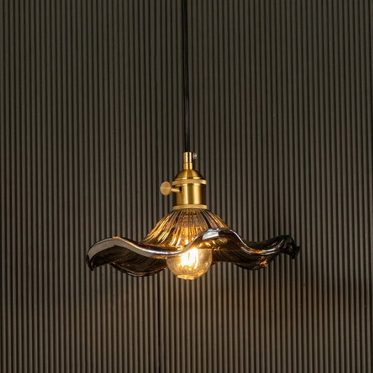 Wavy smoked glass pendant light with a polished metal holder casting soft ambient glow imagined against a dark background creating a dramatic refined interior decor mood.