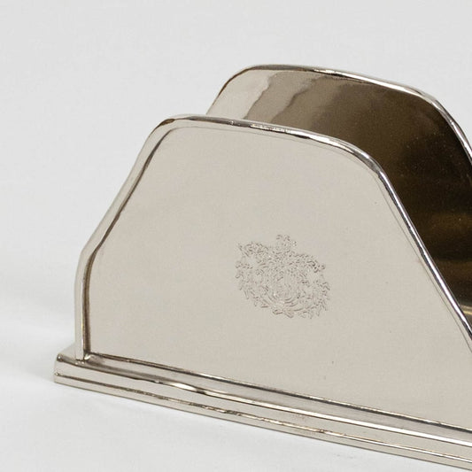 Detailed closeup view of the intricate engraved crest on the polished silver napkin holder surface highlighting craftsmanship.