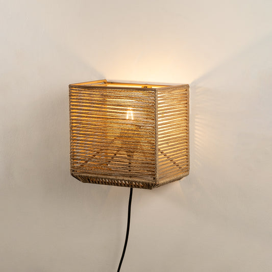 Wall light with woven natural fiber shade emitting warm glow ideal for cozy bedroom or living room wall decor placement.