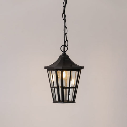 Elegant black outdoor hanging lantern glowing softly on white background ideal for porch garden or entry lighting decor.