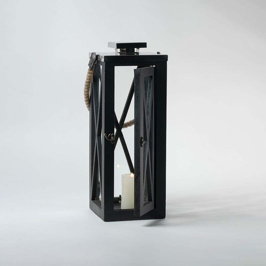 Black lantern illuminated on a white background showcasing the glow through its transparent glass windows.