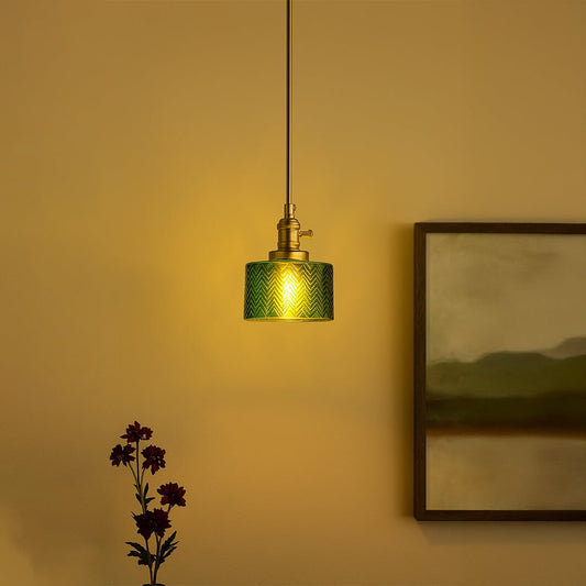 Green glass pendant light with brass holder hanging over modern dining setup adding elegant glow to home interiors.