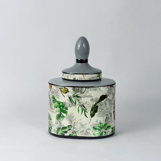 Tropical leaf jar on plain white background with vivid green leaf design and smooth ceramic finish.