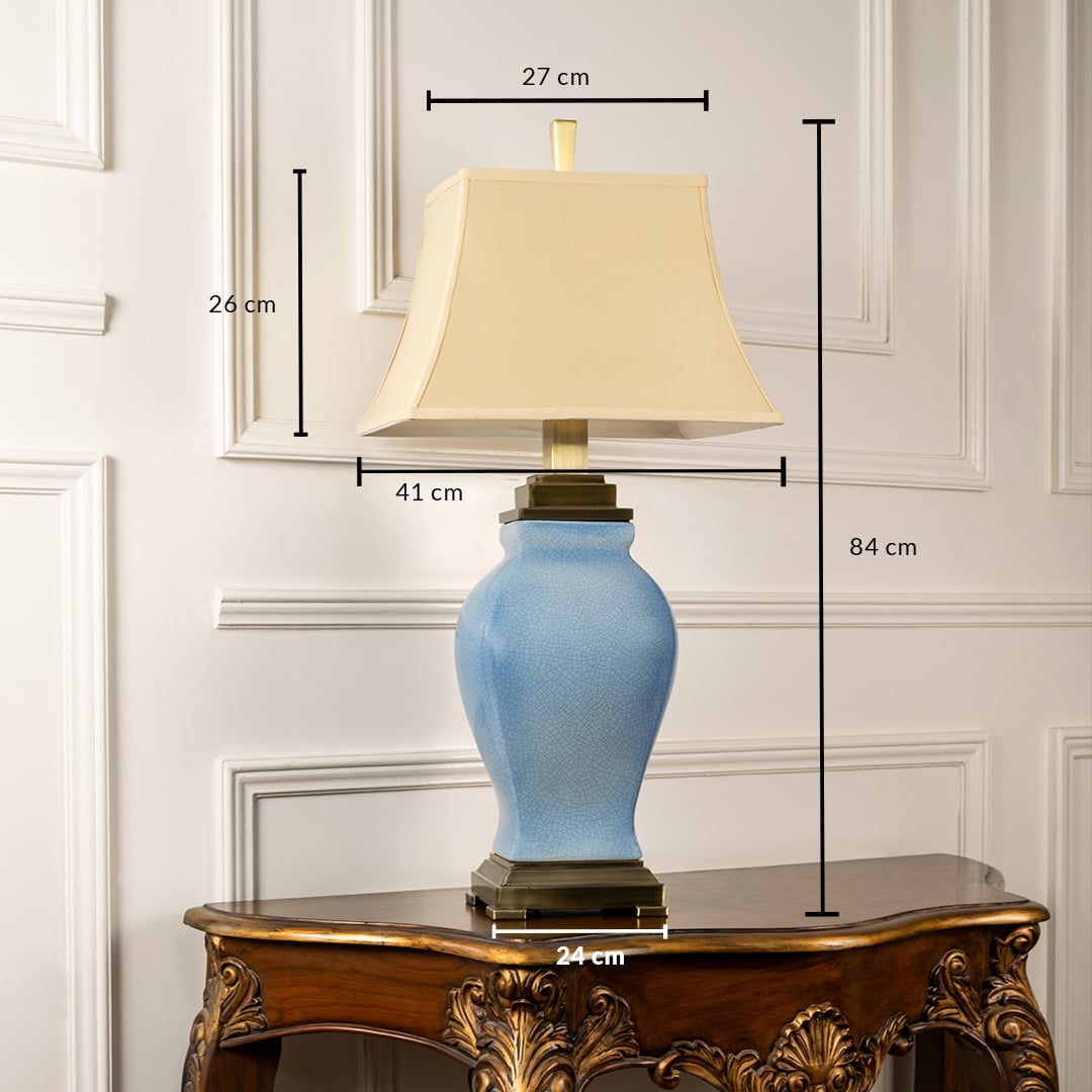 Cream shade blue ceramic table lamp with size 72cm height and 37cm width on carved console table with light on for classic elegant décor.