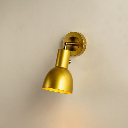 A gold metal wall light glowing with warm brightness on a beige surface creating elegant accent lighting and luxurious modern sconce décor for home interiors.