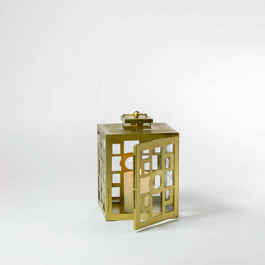 Brass lantern with candle light glowing softly on white background for ambient decor.