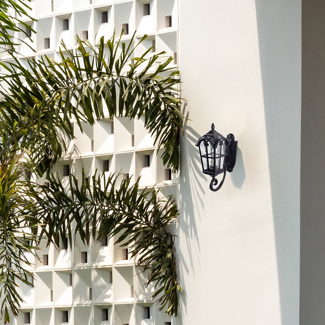 Outdoor wall light mounted on white exterior wall beside greenery creating a fresh and elegant home facade look.