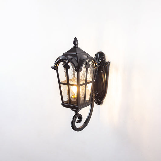 Black metal outdoor wall light on white background with a curved arm bracket and textured glass shade for patio decor.