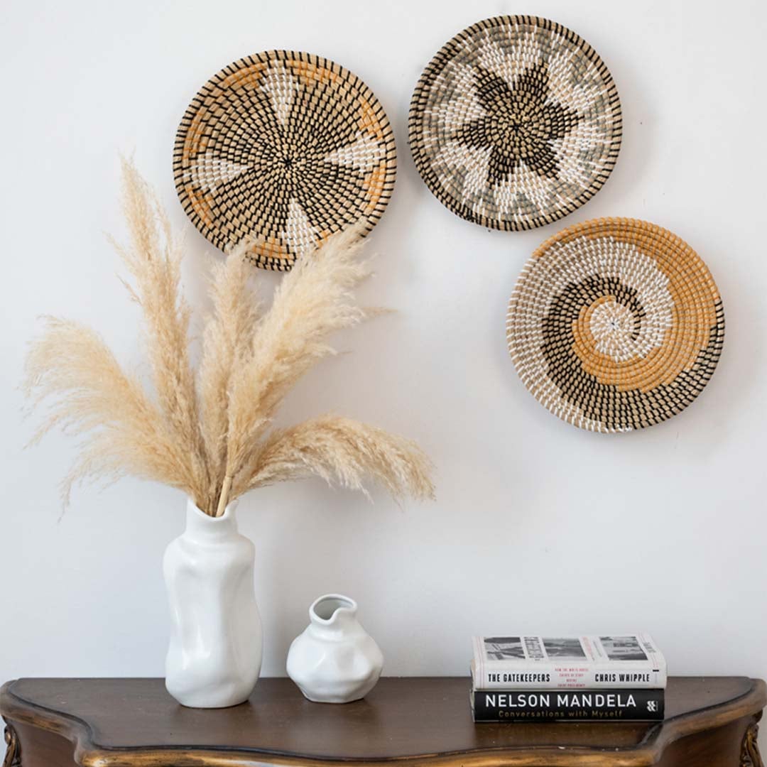 Wicker wall plate styled on a wall with pampas grass in a ceramic vase boho chic basket wall decor for living room and home styling.