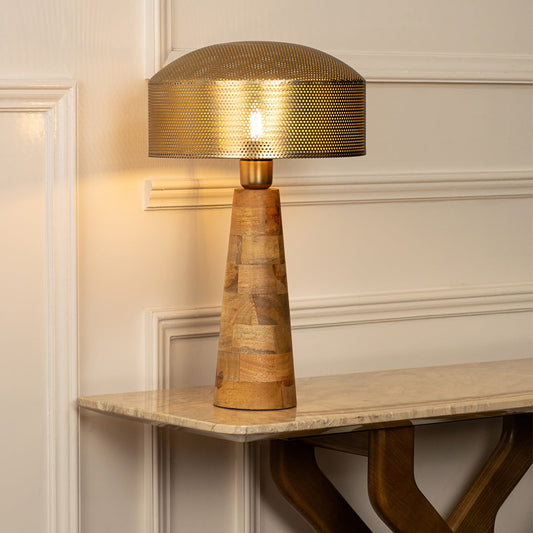 Gold metal table lamp with textured shade and natural wood base casting warm ambient light for luxury interior decor.