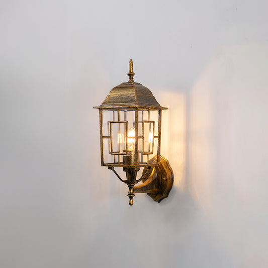 Antique brass metal outdoor wall light on white background with clear paneled glass shade for vintage porch decor.
