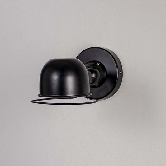 Wall sconce with matte black metal dome shade and cage detail perfect for bedroom living room and industrial style interiors.