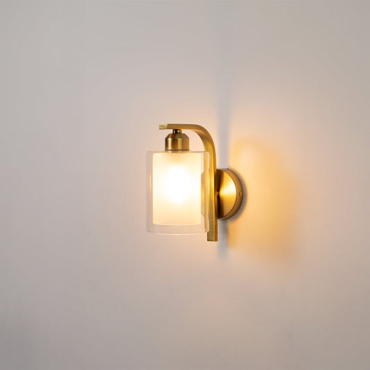 Contemporary brass wall light with frosted glass shade for stylish modern bedroom decor.