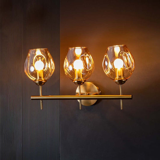Three globe wall light with bulbs glowing warmly against a dark black background creating a dramatic contrast and elegant modern lighting effect.
