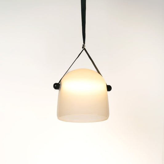 Frosted white glass pendant light illuminated on white background adding soft modern glow to home interiors.