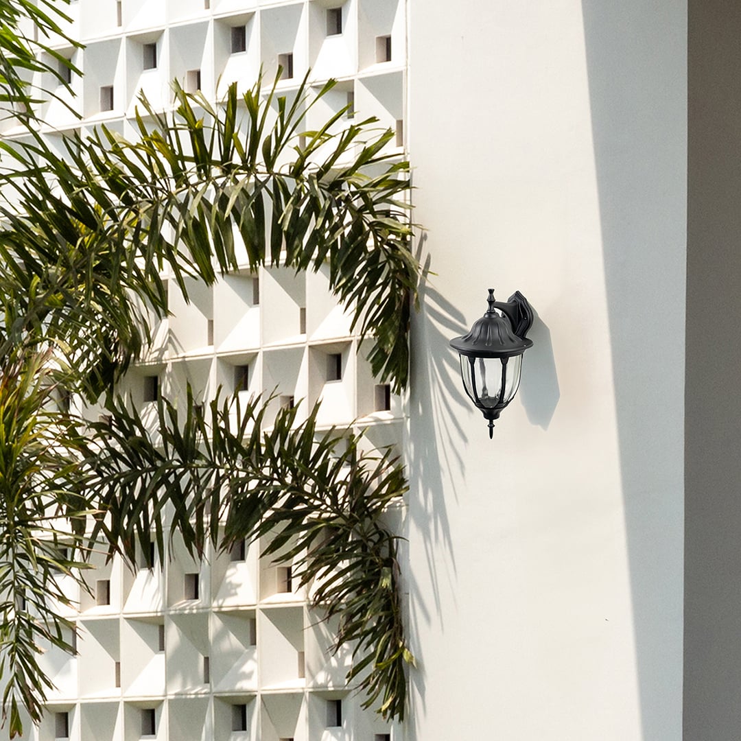 Black metal outdoor wall light lifestyle image on modern exterior wall for elegant patio lighting decor.