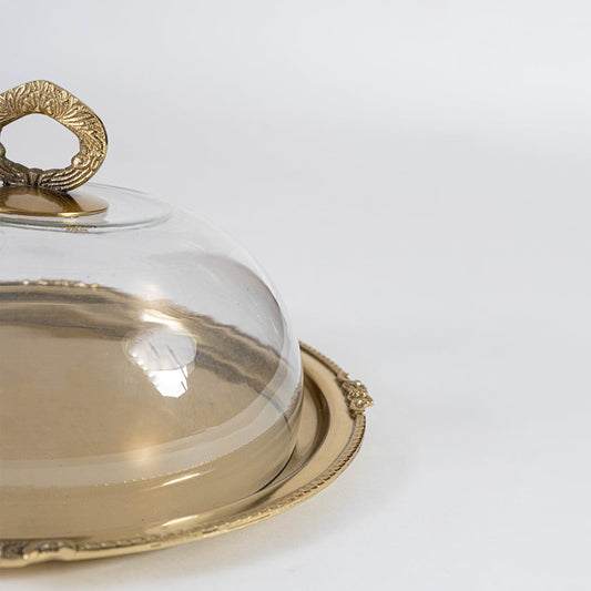 Closeup of brass cloche handle showing the fine engraved detailing and the clear glass dome with emphasis on craftsmanship and texture.