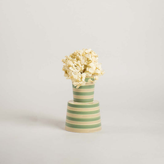 Contemporary striped ceramic vase in green and beige set on a plain white backdrop emphasizing its modern shape and decorative appeal.