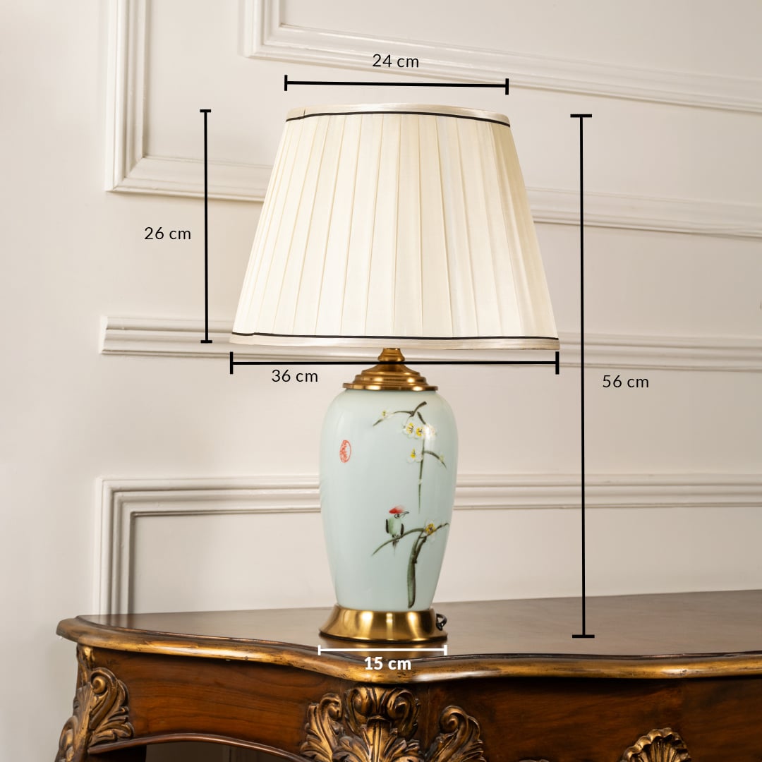 Designer floral ceramic table lamp measuring 56 cm in height and 36 cm in width featuring a gold base and cream pleated shade.