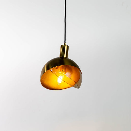 Gold half globe pendant light displayed against a clean white background with the light on showing its warm glow and modern curved metal shade design.
