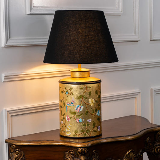 Table lamp on white background featuring yellow ceramic base with colorful floral bird artwork paired with a black fabric lampshade.