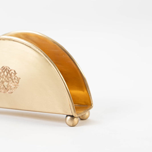 Main product image of half-moon shaped brass napkin holder with floral engraving and clean minimal design.