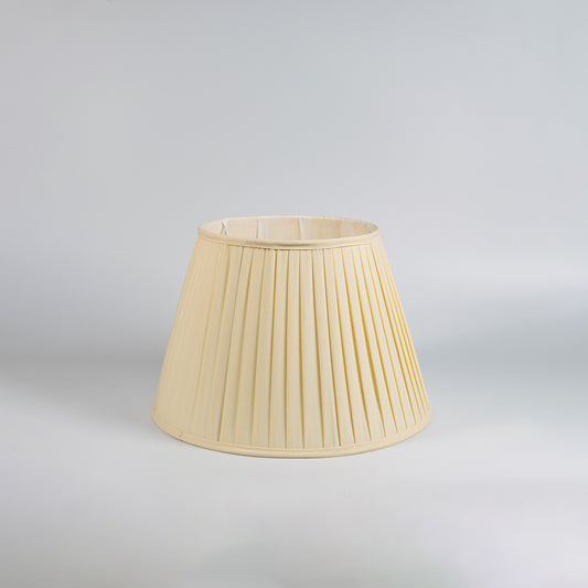 Cream pleated fabric table lamp with textured shade and wooden base designed for bedrooms and living spaces.