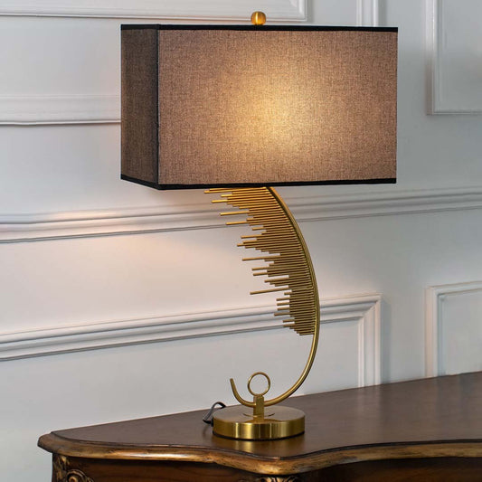Gold metal table lamp with black fabric shade and leaf design base offering luxury decor and warm ambient lighting.