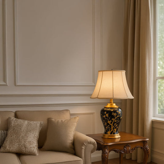 Elegant black and gold ceramic table lamp with beige shade placed on wooden side table illuminating a cozy beige sofa corner creating warm inviting ambiance.