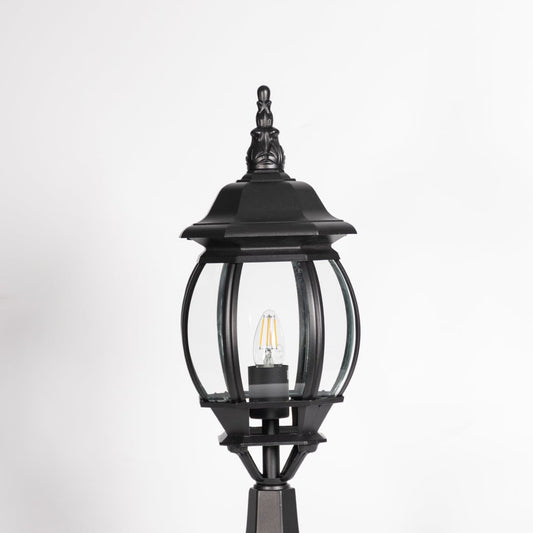 Closeup of decorative outdoor black pillar light with clear curved glass and LED bulb highlighting premium classic design.
