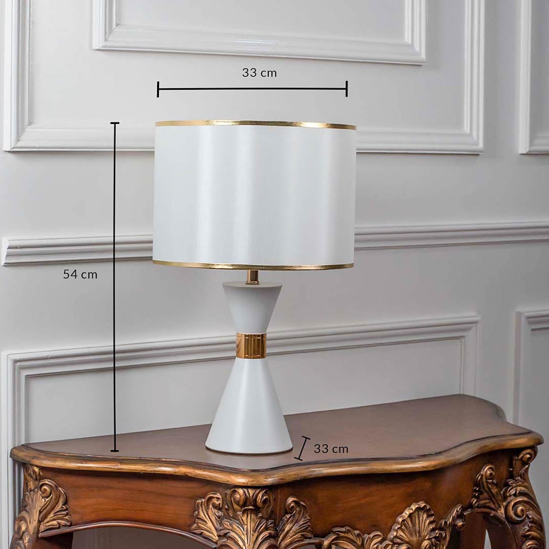 White ceramic table lamp with drum shade and brass detailing shown with 54cm height and 33cm width.