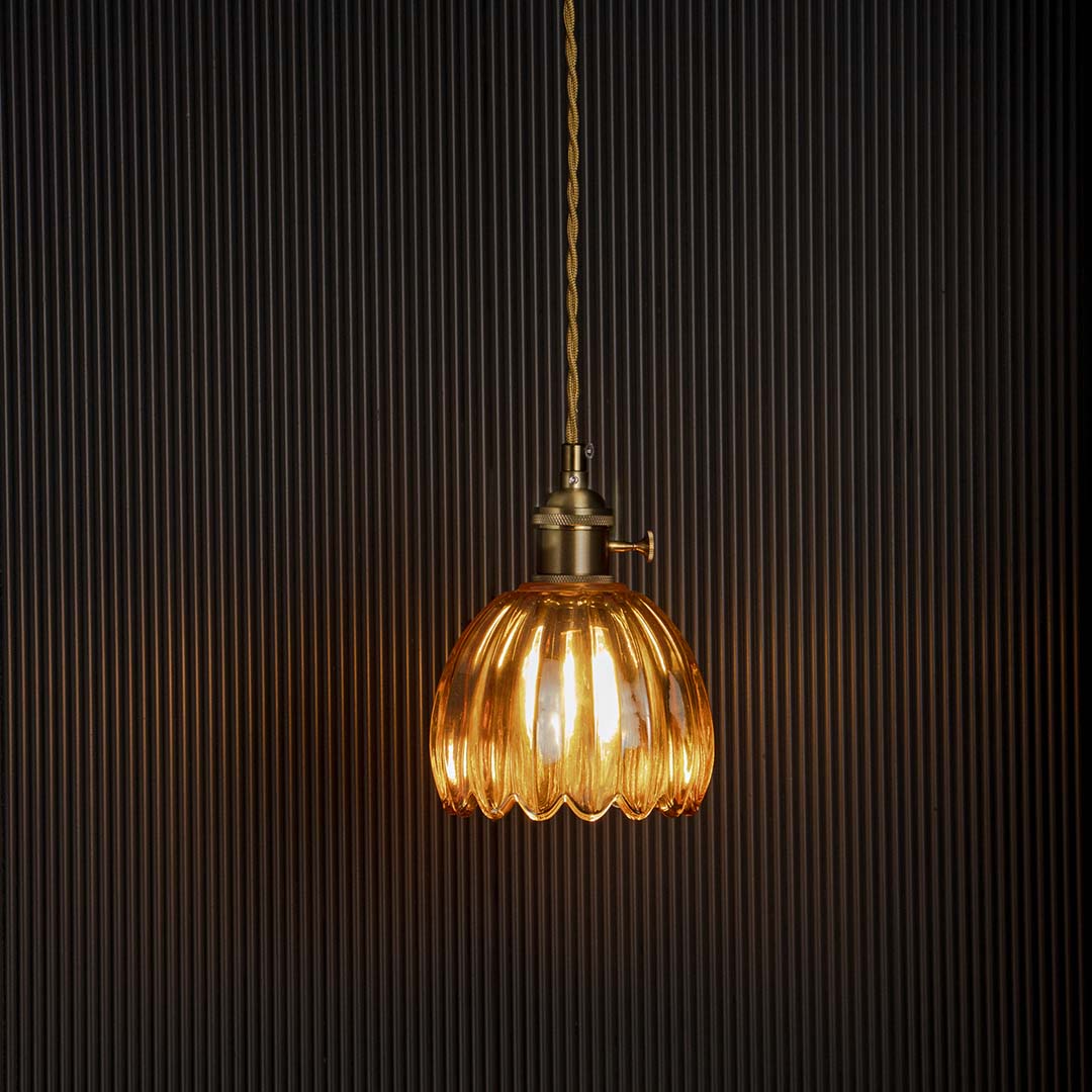 Amber ribbed glass pendant light glowing warmly on black background adding elegance to bedroom dining and interiors.