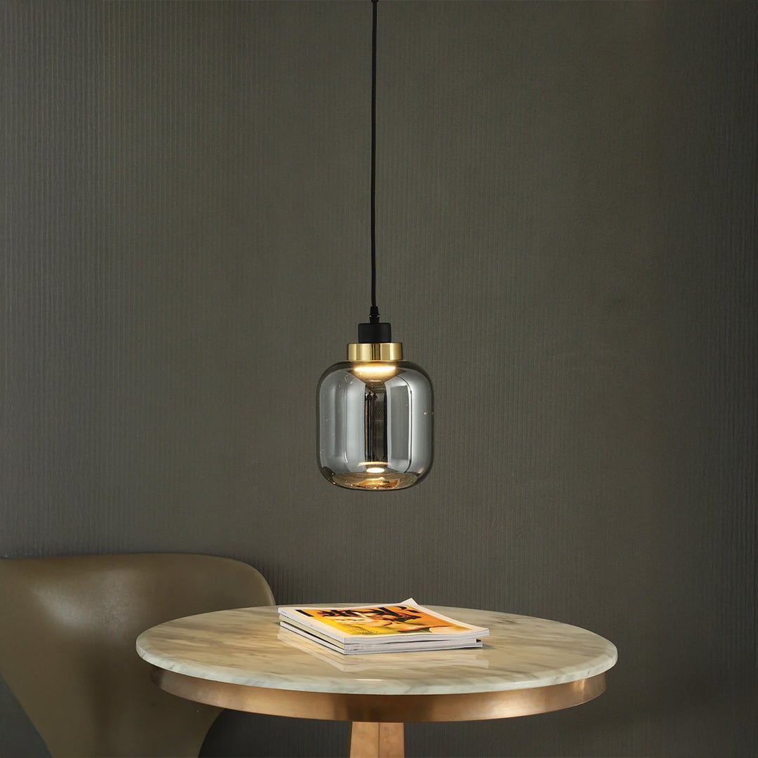 Smoky glass pendant light with warm glow adding sophisticated charm to dining room settings.