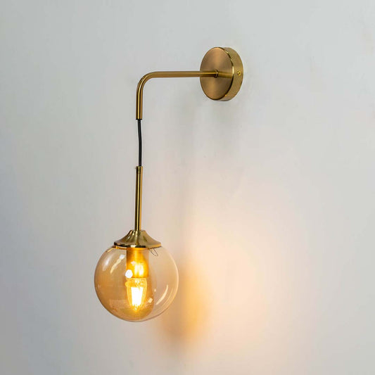 Gold and smoked glass wall light with bulb on against a white background showing warm illumination and a stylish modern dual shade design.