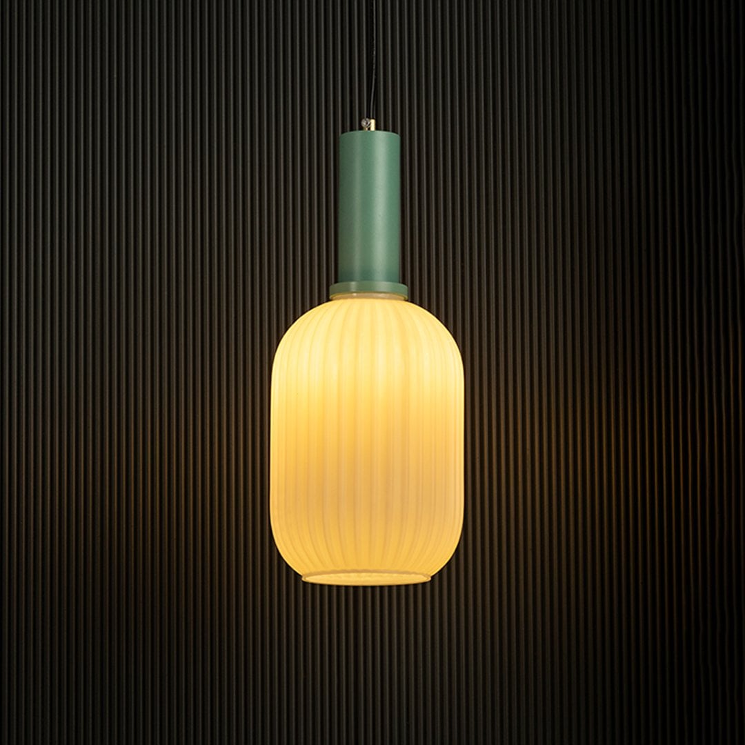 Contemporary ribbed glass pendant light with green finish glowing against a dark background.