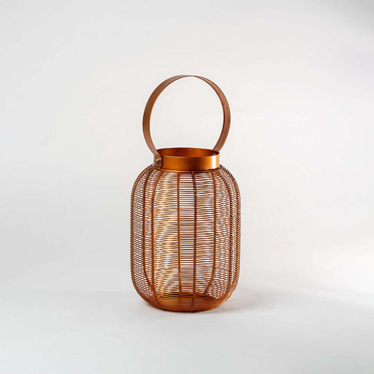 Copper metal mesh cylindrical lantern with circular carrying handle and ribbed texture design on isolated white background.